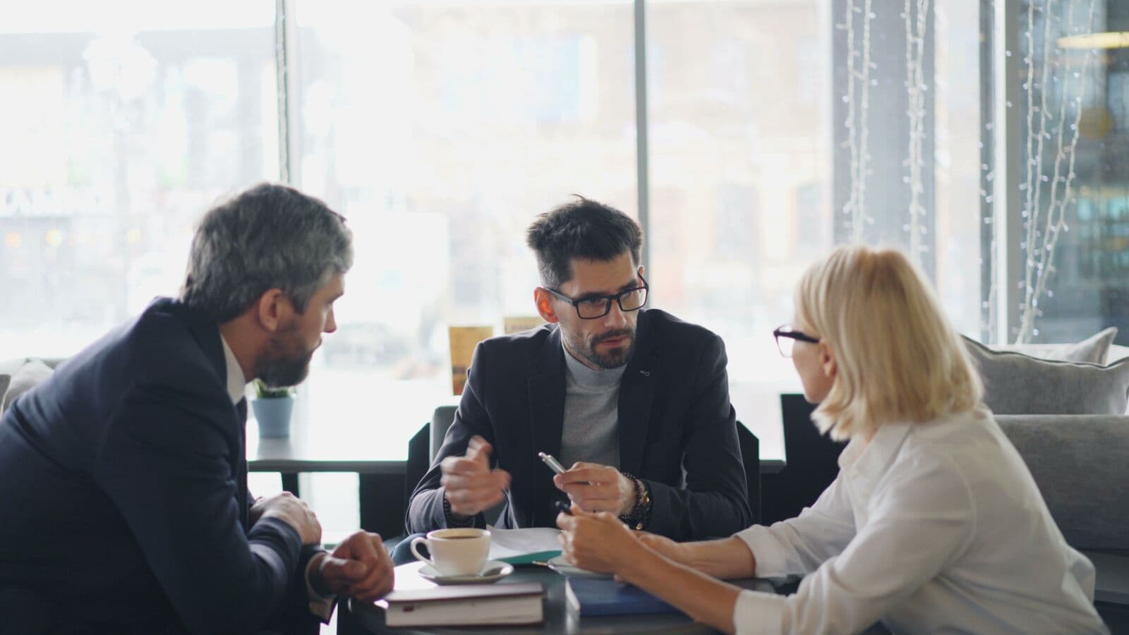 Three people talking around a café table