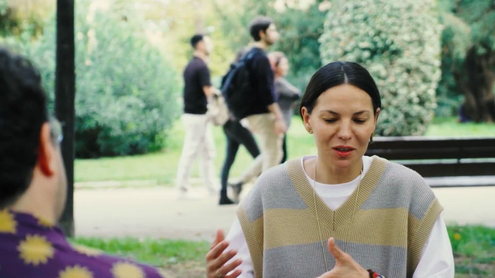 A woman talking with someone across from her in a park